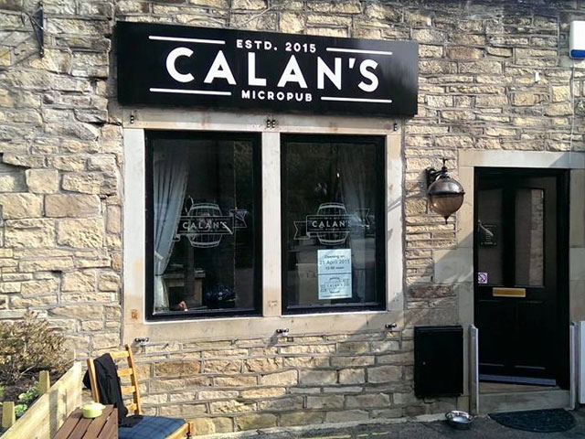 A stone building with a large sign above two small windows. The sign reads Calan's Micropub ested. 2015