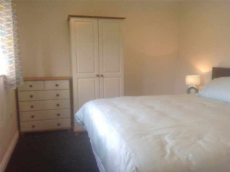 Bedroom showing double bed, chest of draws and a wardrobe